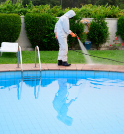 A man in white suit cleaning the pool.
