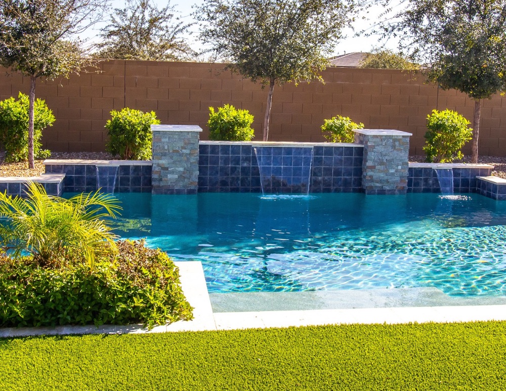 Swimming pool with raised wall and multiple cascading water features